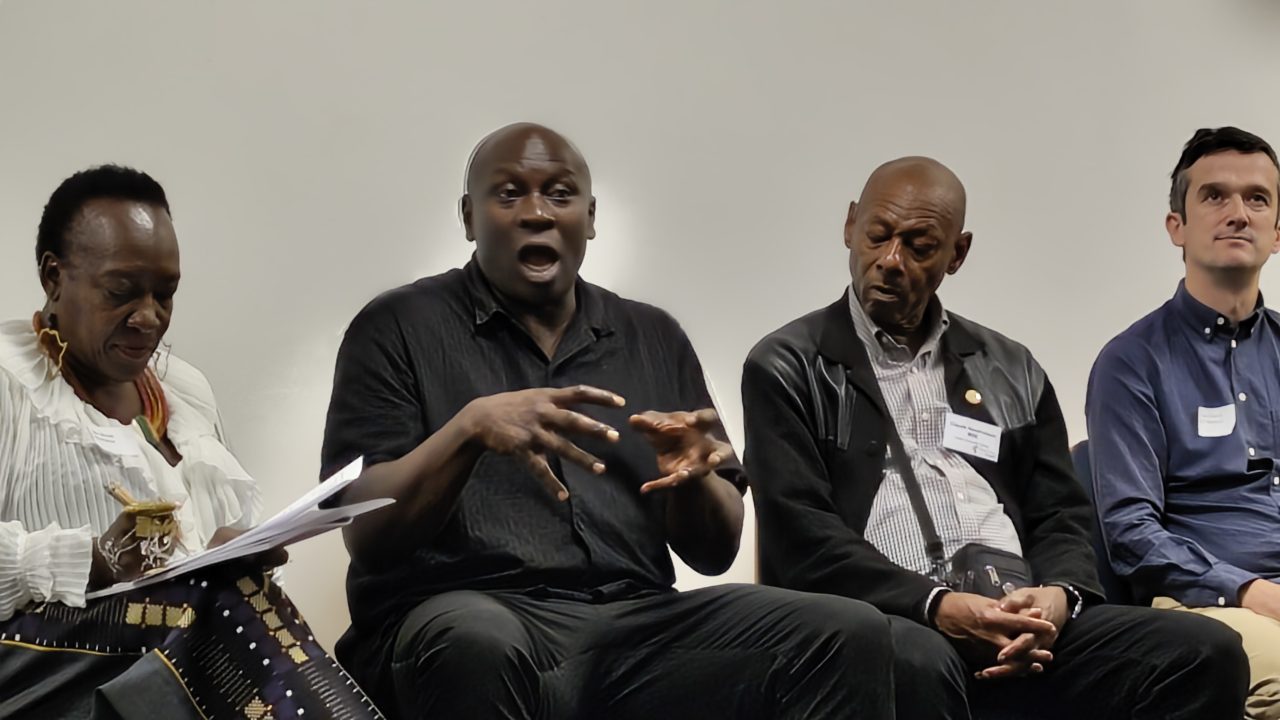 Beverly Brown, Tim Oshodi, Claude Hendrickson and Tom Chance are seated in a row. Tim is speaking and the other three people in the image are listening